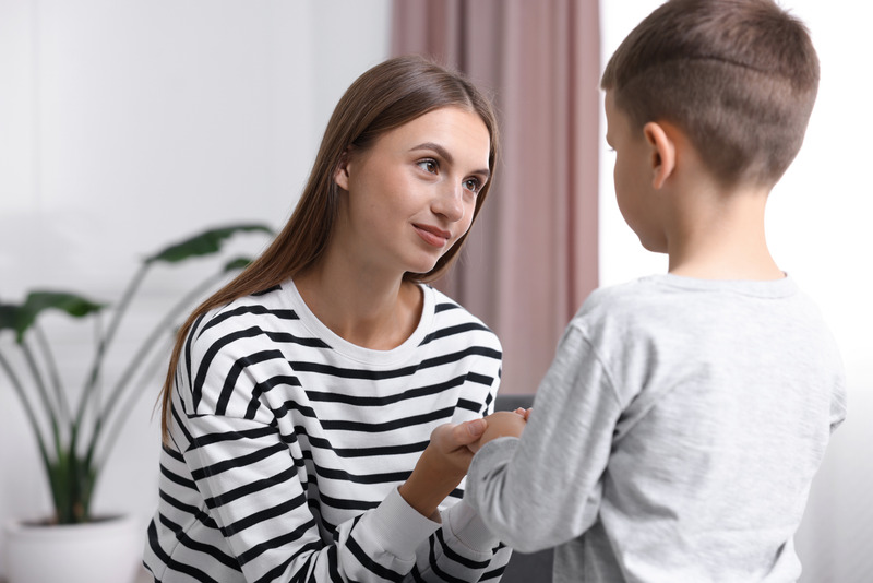 Madre hablando con su hijo de forma tranquila mientras le sujeta las manos.