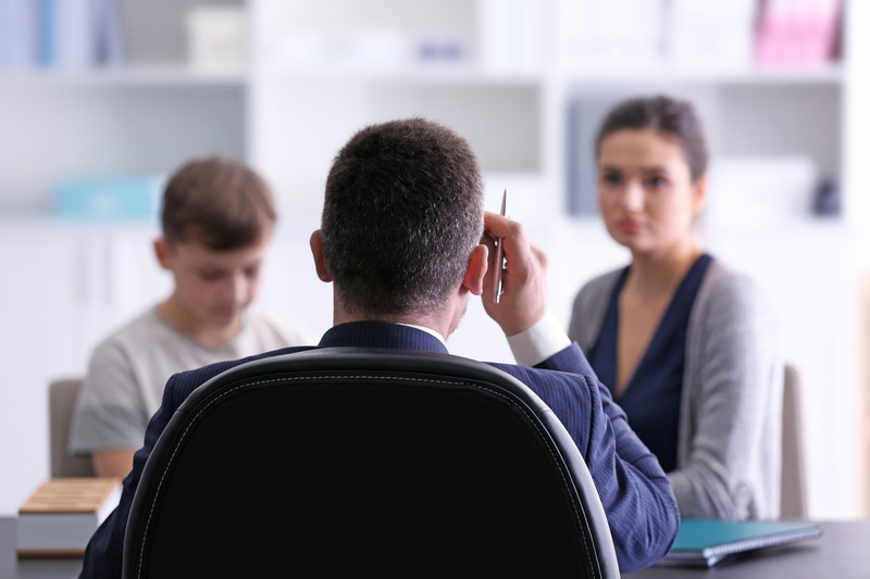 Madre con su hijo en una reunión con el director del colegio.
