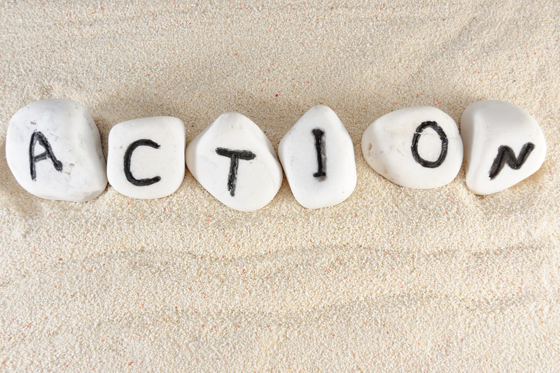 Seis piedras sobre la arena, cada una con una letra de la palabra action.