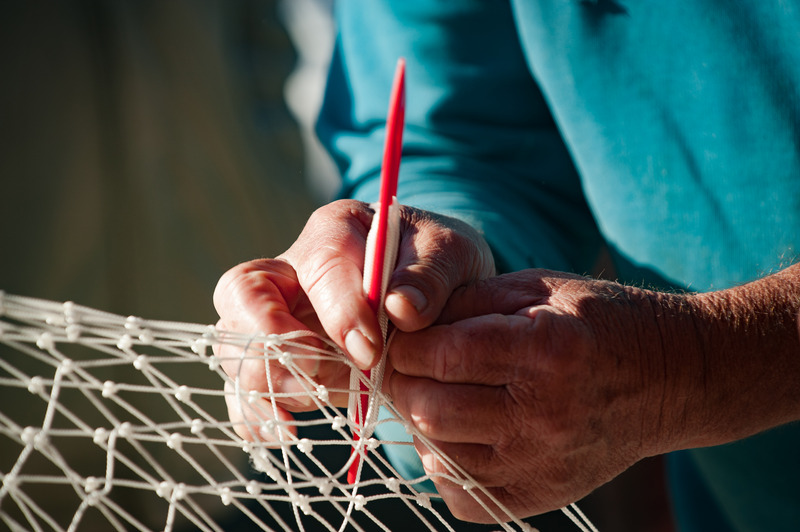 Manos de un pescador cosiendo una red, metáfora visual de cómo se construyen conexiones mentales con puentes mnemotécnicos.